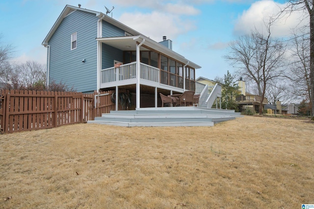 back of house featuring a wooden deck, a yard, and a sunroom