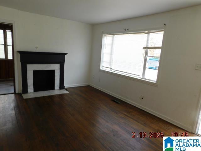 unfurnished living room featuring plenty of natural light and dark hardwood / wood-style flooring