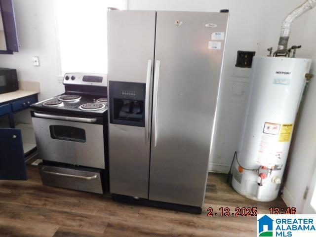 kitchen featuring dark wood-type flooring, stainless steel appliances, water heater, and blue cabinets