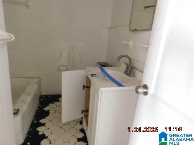 bathroom featuring tile walls, vanity, and a washtub