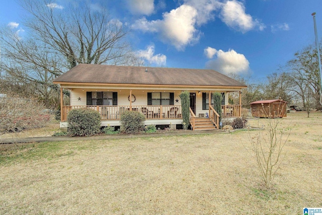 view of front of home featuring a front yard, a storage unit, and covered porch