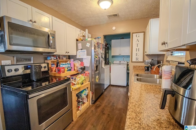 kitchen featuring appliances with stainless steel finishes, washer and dryer, dark hardwood / wood-style floors, sink, and white cabinets