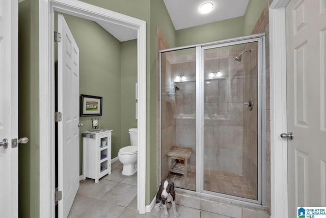 bathroom featuring a shower with shower door, tile patterned floors, and toilet