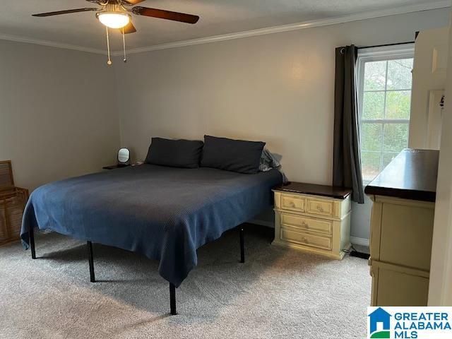 bedroom with ceiling fan, crown molding, and light colored carpet