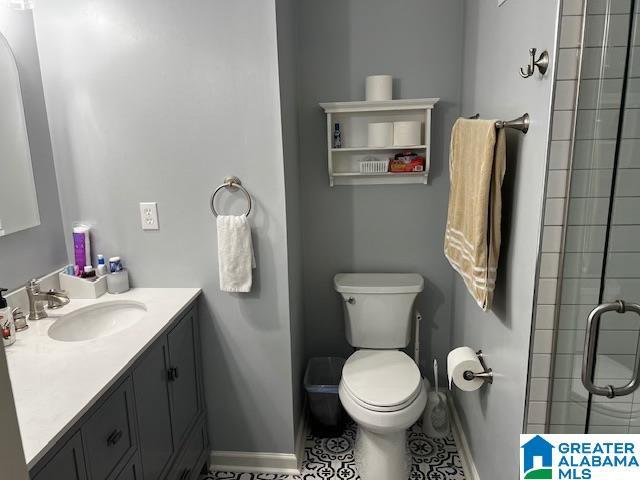 bathroom with a shower with shower door, vanity, and toilet