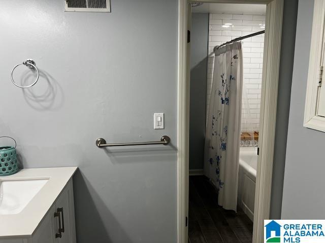 bathroom featuring hardwood / wood-style flooring, vanity, and shower / bath combo with shower curtain