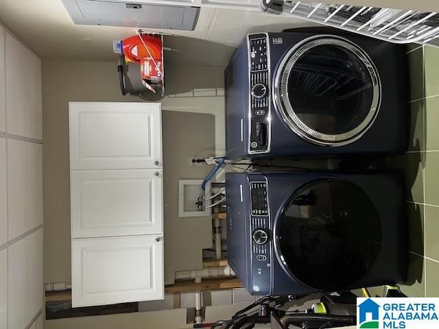 washroom with stacked washer / drying machine and cabinets