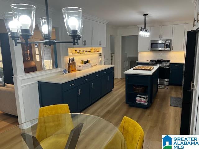 kitchen featuring white cabinets, a center island, appliances with stainless steel finishes, and decorative light fixtures