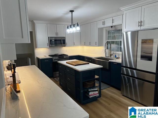 kitchen with light stone counters, decorative light fixtures, stainless steel appliances, white cabinets, and decorative backsplash