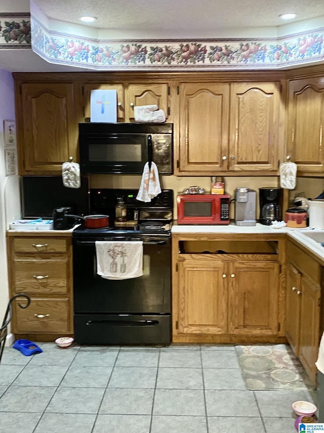 kitchen with light tile patterned floors, a textured ceiling, and black appliances