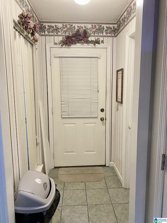 doorway with light tile patterned flooring and a textured ceiling