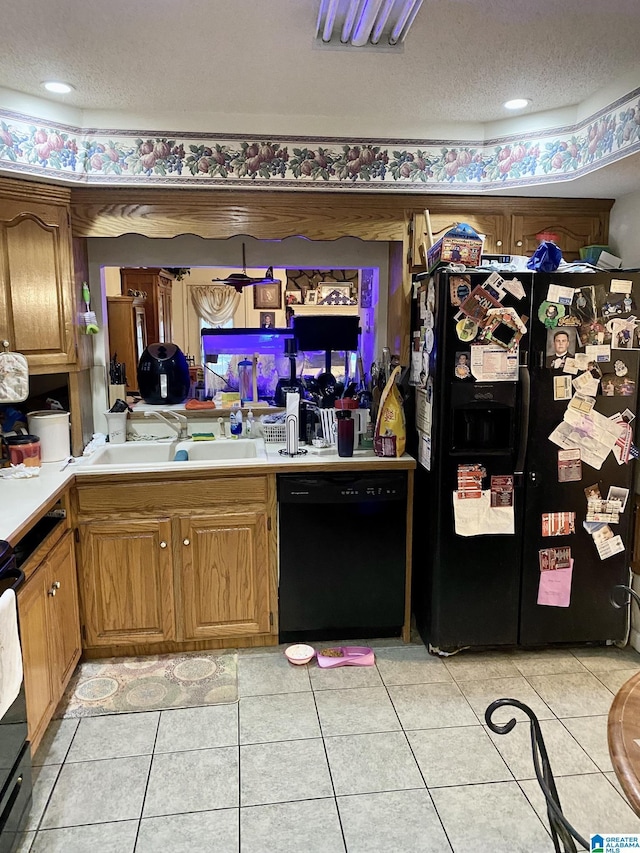 kitchen with light tile patterned floors, sink, a textured ceiling, and black appliances