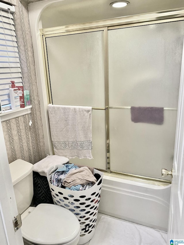 bathroom with enclosed tub / shower combo and toilet