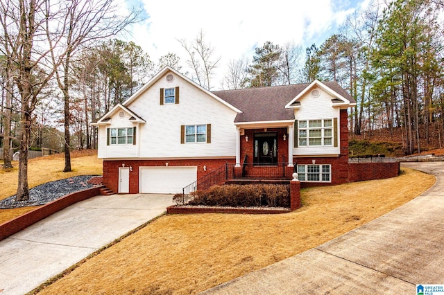 split foyer home featuring brick siding, driveway, an attached garage, and a front lawn