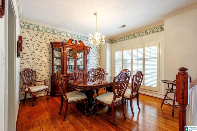 dining area with hardwood / wood-style flooring, crown molding, a textured ceiling, and a chandelier