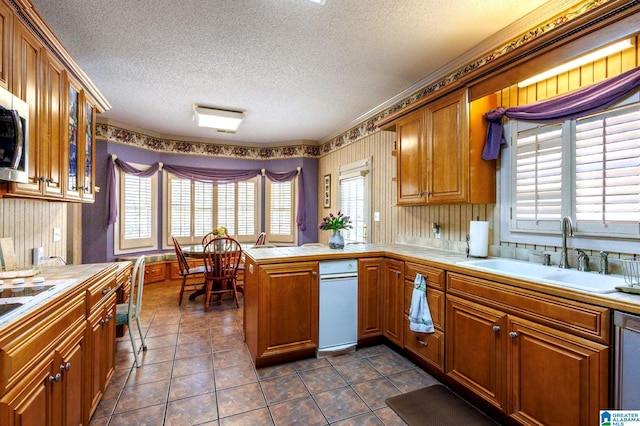 kitchen with dishwasher, sink, dark tile patterned flooring, kitchen peninsula, and a textured ceiling