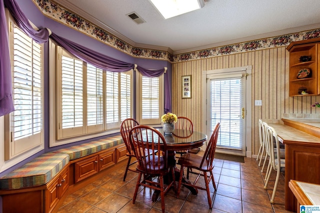 dining room featuring ornamental molding, a textured ceiling, and dark tile patterned floors