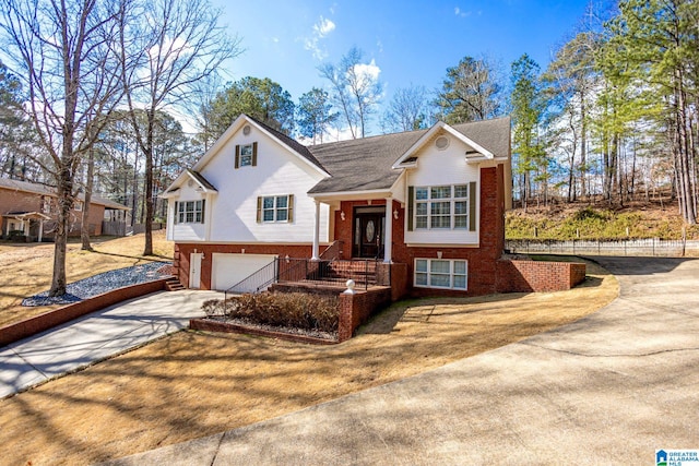 raised ranch featuring brick siding, concrete driveway, and a garage