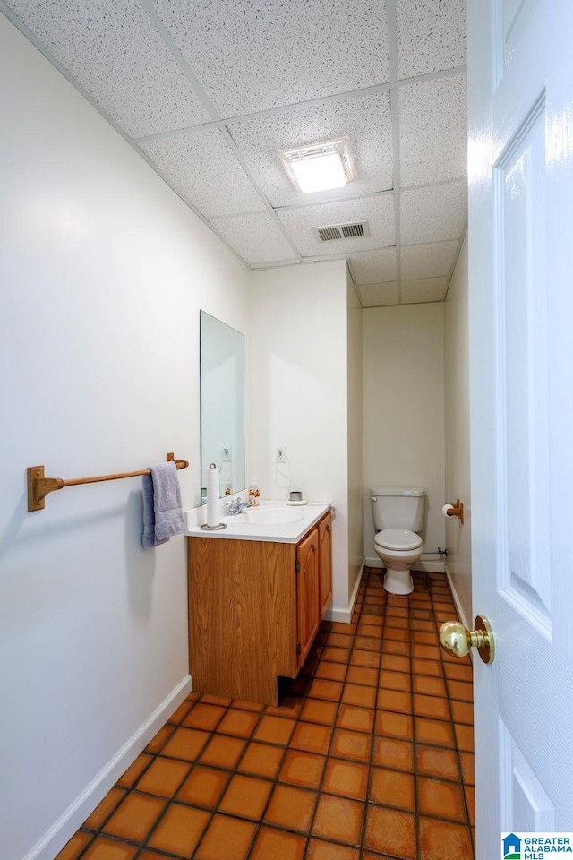 bathroom featuring vanity, a paneled ceiling, tile patterned floors, and toilet