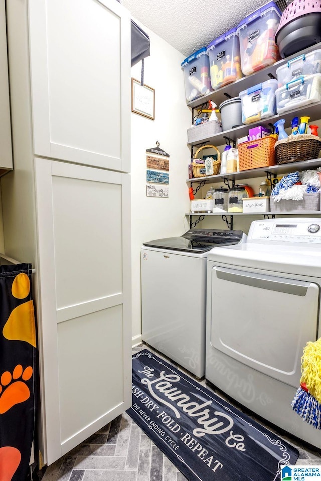 laundry area with cabinets, a textured ceiling, and washer and clothes dryer