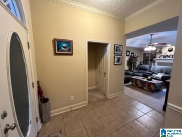 interior space with crown molding, ceiling fan, tile patterned flooring, and a textured ceiling