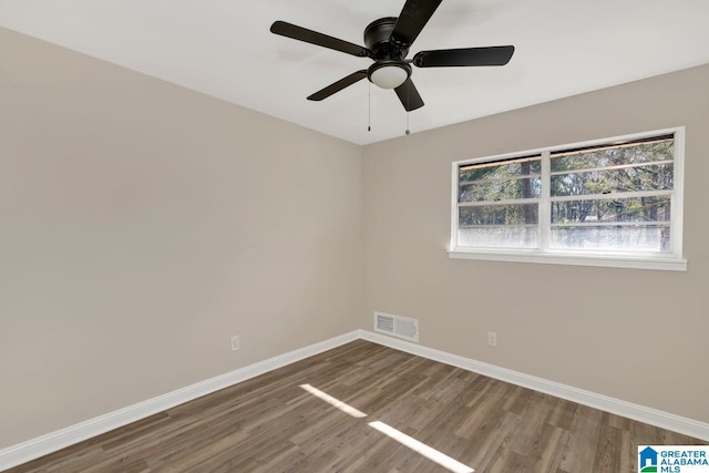 empty room with baseboards, visible vents, ceiling fan, and wood finished floors