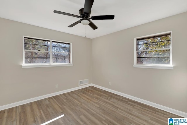 unfurnished bedroom featuring multiple windows, wood finished floors, and baseboards