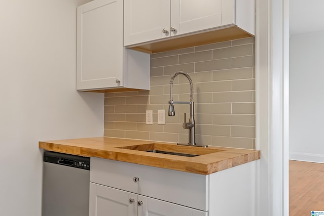 kitchen featuring white cabinetry, dishwasher, butcher block counters, and tasteful backsplash