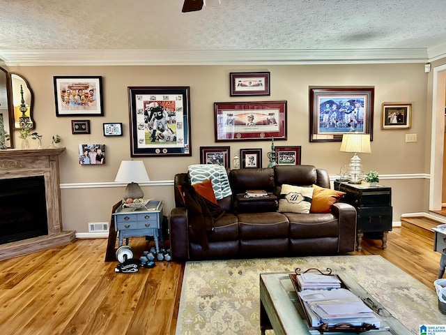 living room featuring crown molding, ceiling fan, a textured ceiling, and hardwood / wood-style flooring