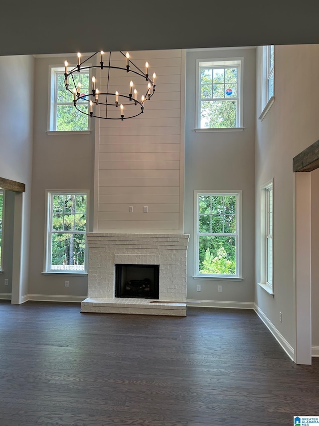 unfurnished living room with a brick fireplace, dark wood-type flooring, and a wealth of natural light