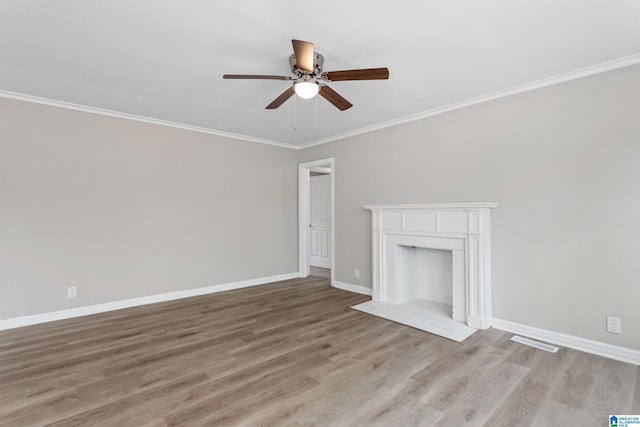 unfurnished living room featuring crown molding, ceiling fan, a fireplace, and light wood-type flooring