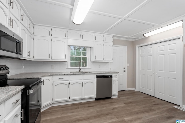 kitchen featuring sink, hardwood / wood-style flooring, white cabinetry, stainless steel appliances, and light stone counters