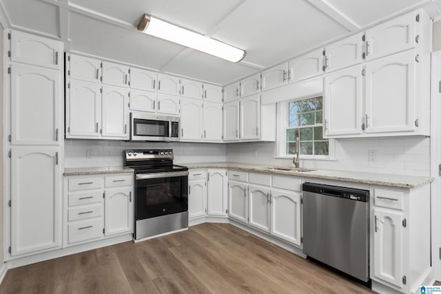 kitchen with sink, stainless steel appliances, tasteful backsplash, white cabinets, and light wood-type flooring