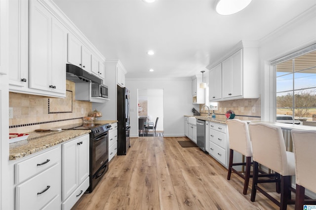 kitchen featuring crown molding, pendant lighting, white cabinets, and black appliances