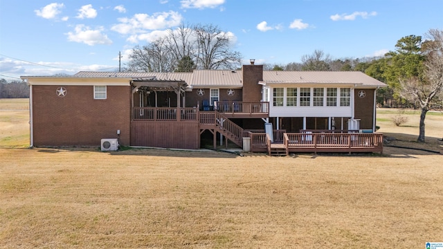 rear view of property featuring a sunroom, a pergola, a deck, and a lawn