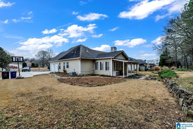 view of side of home with cooling unit, a garage, and a lawn