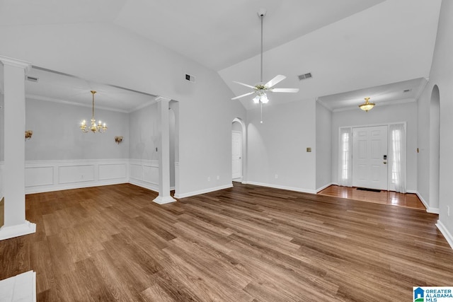 unfurnished living room with ceiling fan with notable chandelier, ornamental molding, ornate columns, and hardwood / wood-style floors