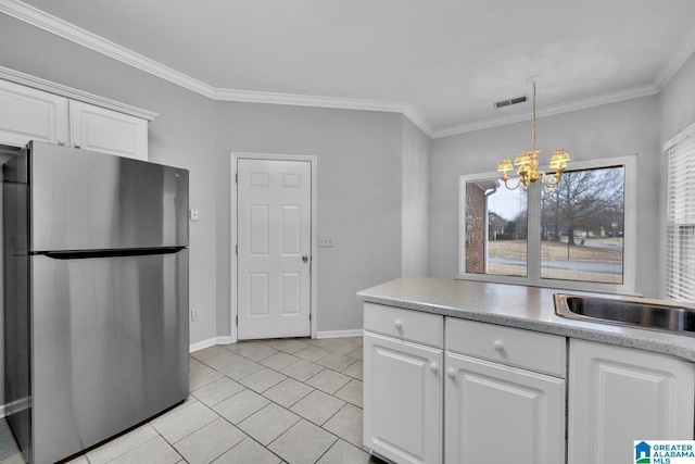 kitchen with stainless steel refrigerator, white cabinetry, a notable chandelier, and ornamental molding