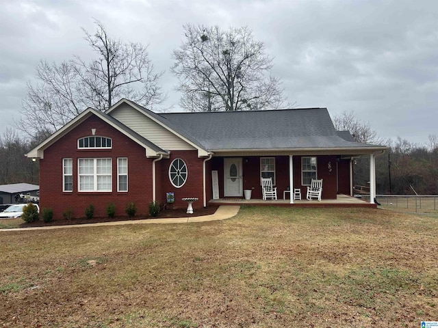 view of front of house featuring covered porch, brick siding, a front yard, and fence