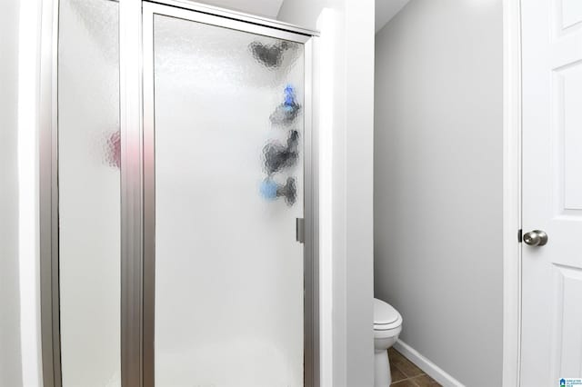 full bath featuring toilet, a stall shower, and tile patterned floors