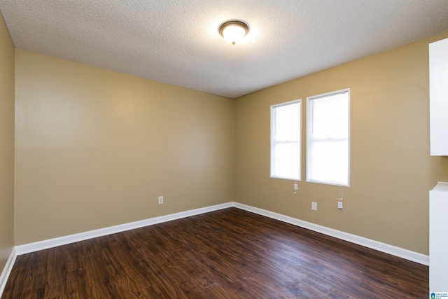 empty room with dark hardwood / wood-style floors and a textured ceiling