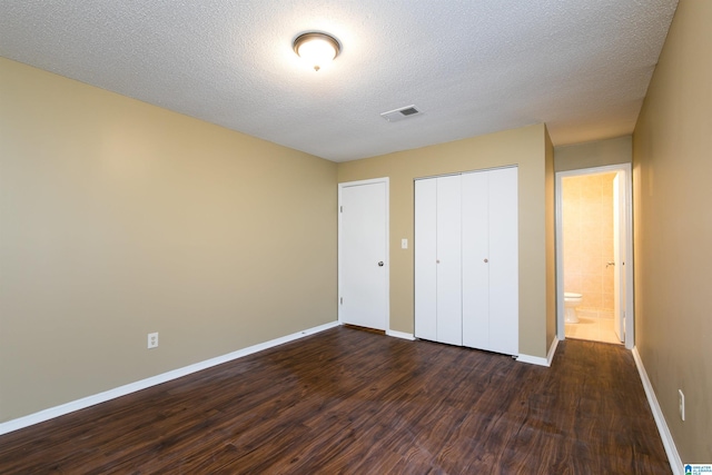 unfurnished bedroom with dark hardwood / wood-style floors, a textured ceiling, and a closet