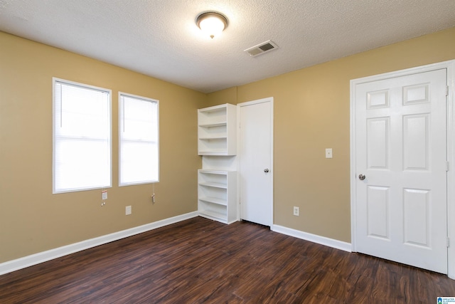 unfurnished bedroom featuring dark wood-type flooring, a closet, and a textured ceiling