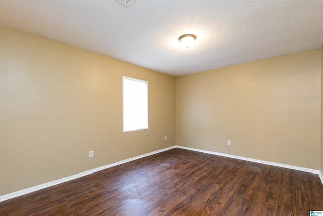 empty room with dark hardwood / wood-style floors and a textured ceiling