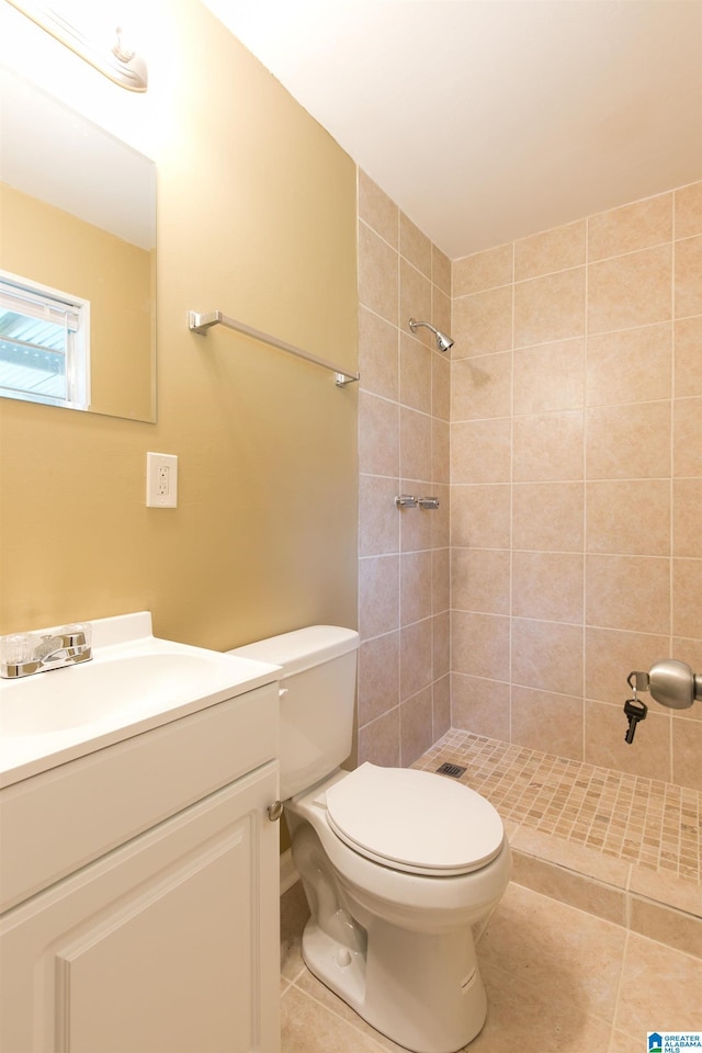 bathroom featuring vanity, toilet, tile patterned flooring, and a tile shower