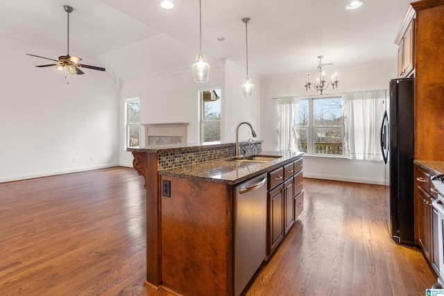 kitchen with black refrigerator, dishwasher, sink, hanging light fixtures, and a kitchen island with sink