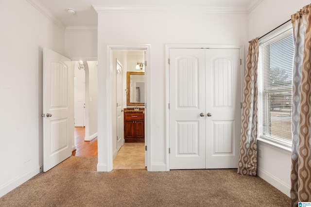 unfurnished bedroom with ornamental molding, light colored carpet, a closet, and ensuite bathroom