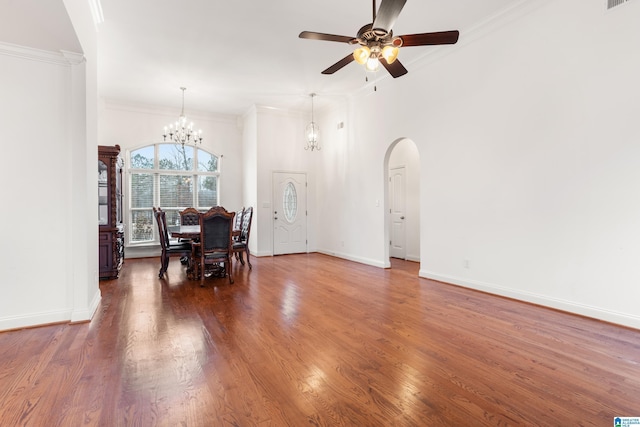 dining area with ornamental molding, dark hardwood / wood-style floors, ceiling fan with notable chandelier, and a towering ceiling