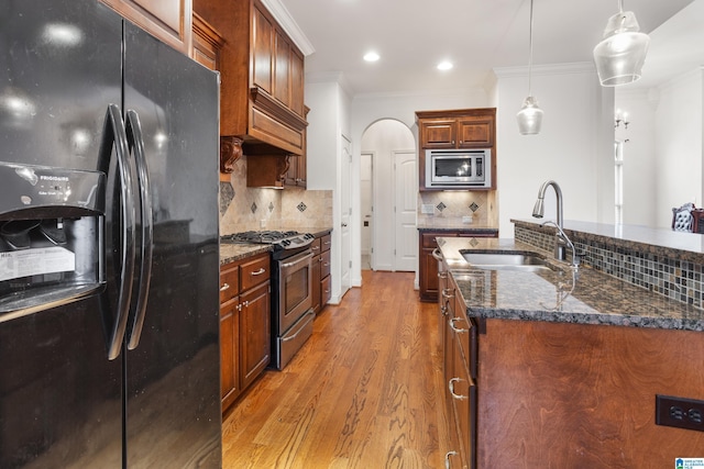 kitchen featuring sink, hanging light fixtures, ornamental molding, hardwood / wood-style flooring, and stainless steel appliances