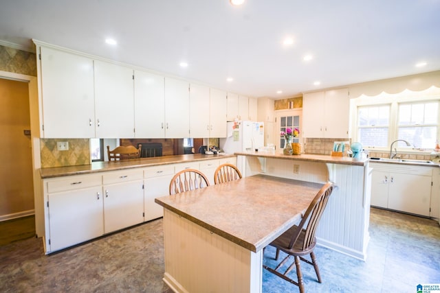 kitchen featuring sink, a breakfast bar, white cabinets, and a center island